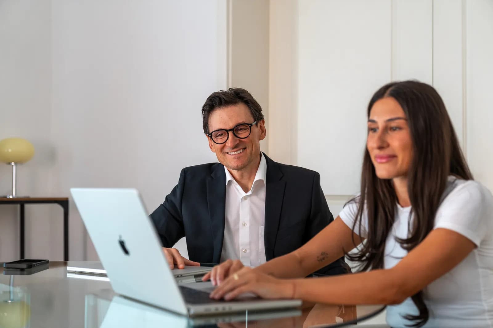 Zwei Personen arbeiten gemeinsam am Laptop in einer Kanzlei